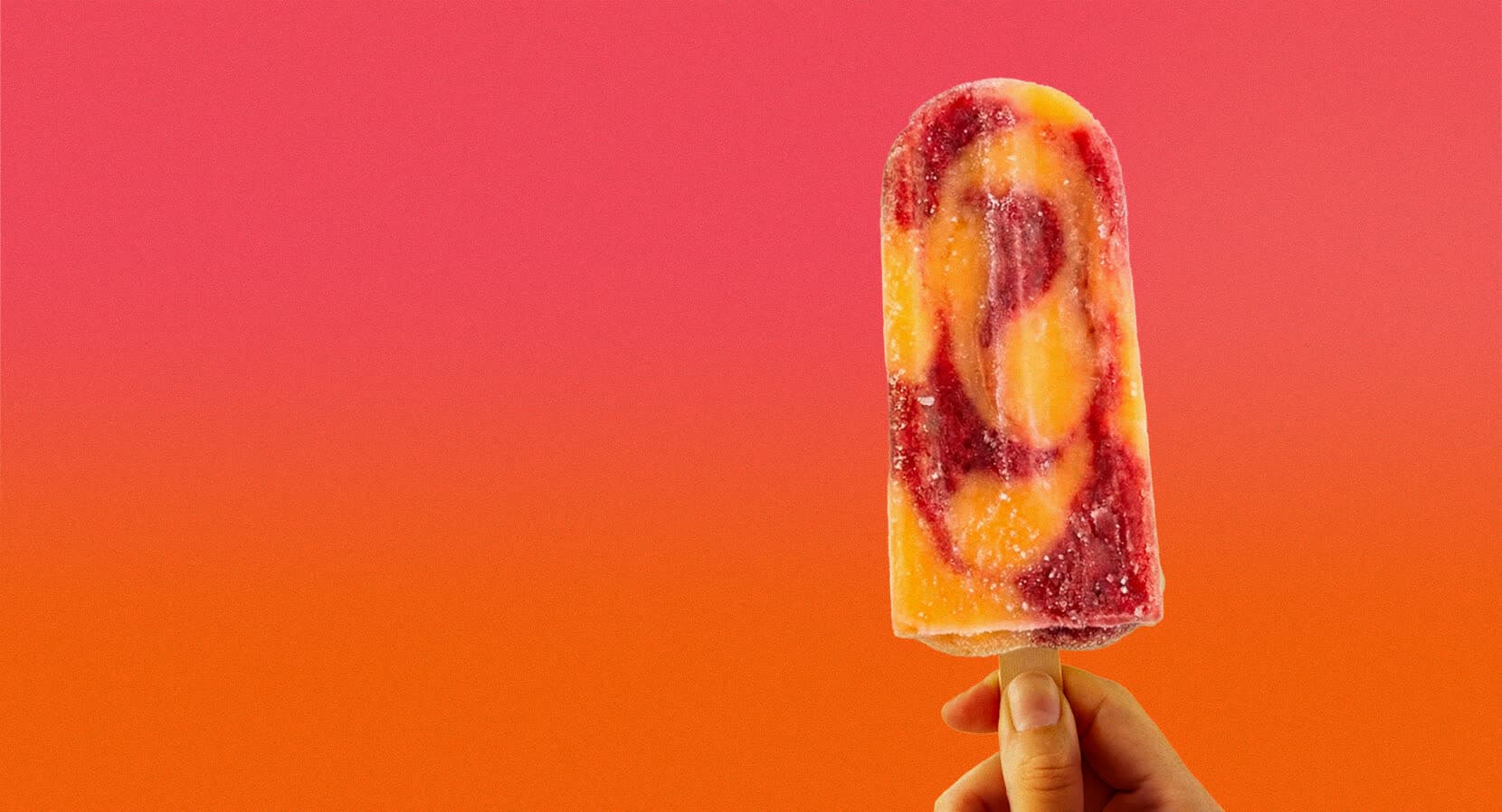 LA Paleta popsicle with mango and raspberry swirl, held against a coral-to-orange sunset gradient.