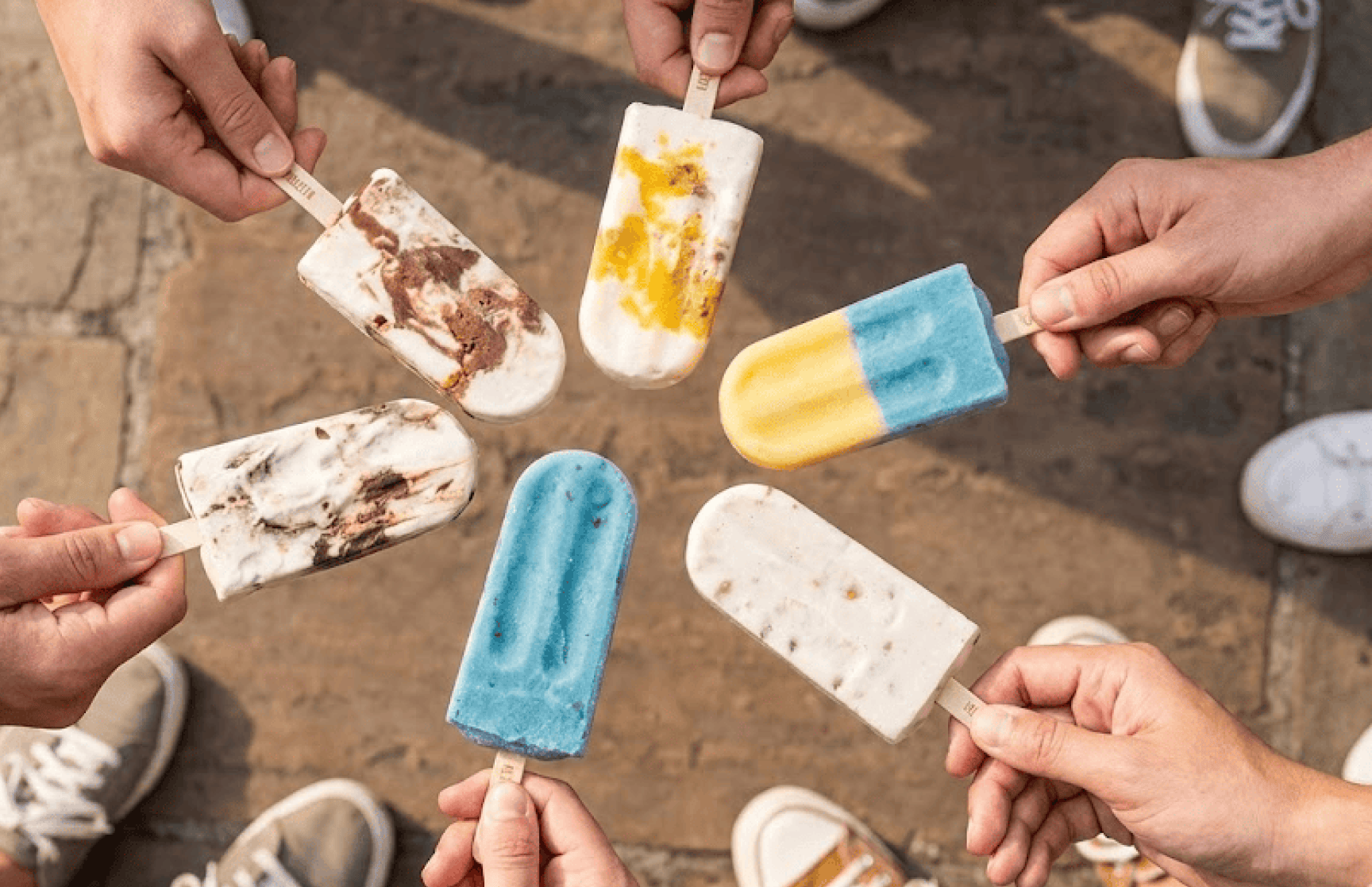 Friends bringing colorful paletas together in a cheers